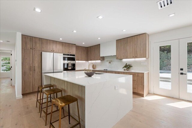 902 Challenger St, Lakeway, TX 78734 - kitchen with appliances with stainless steel finishes, light wood-style floors, modern cabinets, a sink, and french doors