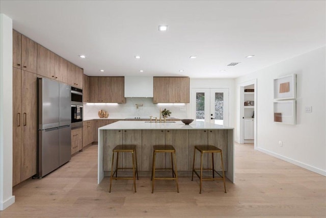 902 Challenger St, Lakeway, TX 78734 - kitchen featuring appliances with stainless steel finishes, modern cabinets, a breakfast bar, light wood finished floors, and recessed lighting