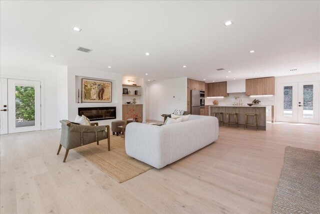902 Challenger St, Lakeway, TX 78734 - living room with french doors, light wood-style floors, recessed lighting, and a glass covered fireplace