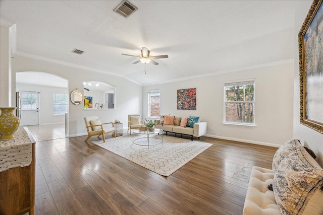 104 Lucky Clover Ln, Hutto, TX 78634 - living room featuring ornamental molding, a ceiling fan, arched walkways, baseboards, and wood finished floors