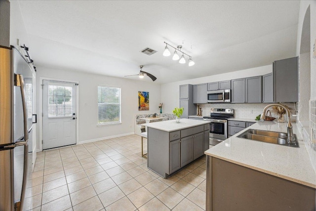 104 Lucky Clover Ln, Hutto, TX 78634 - kitchen with appliances with stainless steel finishes, a sink, gray cabinets, decorative backsplash, and light tile patterned floors