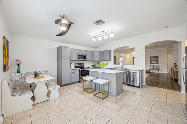104 Lucky Clover Ln, Hutto, TX 78634 - kitchen with appliances with stainless steel finishes, gray cabinets, a sink, light countertops, and a breakfast bar