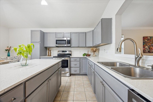 104 Lucky Clover Ln, Hutto, TX 78634 - kitchen featuring appliances with stainless steel finishes, gray cabinetry, a sink, decorative backsplash, and light tile patterned floors