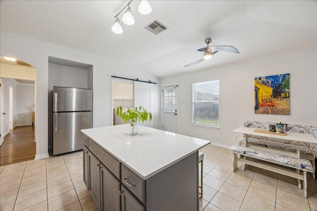 104 Lucky Clover Ln, Hutto, TX 78634 - kitchen with freestanding refrigerator, a barn door, a center island, light tile patterned floors, and ceiling fan