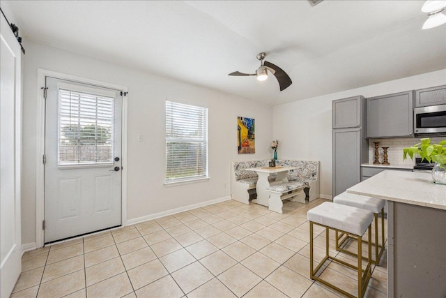 104 Lucky Clover Ln, Hutto, TX 78634 - kitchen featuring gray cabinetry, a ceiling fan, stainless steel microwave, light tile patterned floors, and baseboards