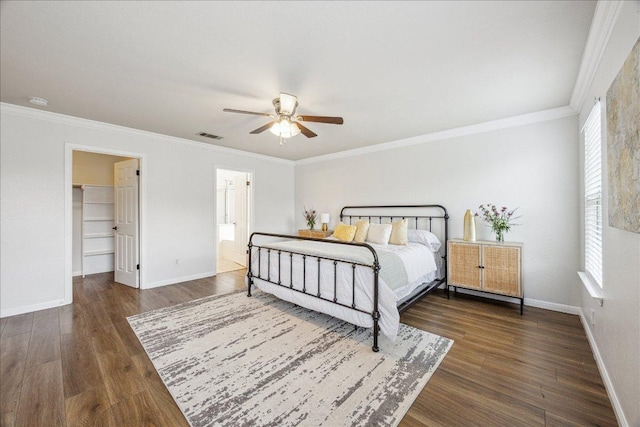 104 Lucky Clover Ln, Hutto, TX 78634 - bedroom featuring wood finished floors, baseboards, ornamental molding, and a walk in closet