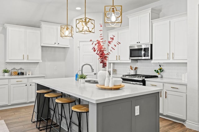 217 Magdalene Way, Liberty Hill, TX 78642 - kitchen with light wood finished floors, tasteful backsplash, a kitchen island with sink, stainless steel microwave, and white cabinets