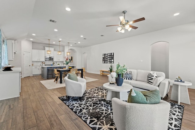 217 Magdalene Way, Liberty Hill, TX 78642 - living room featuring arched walkways, light wood-style floors, a ceiling fan, and recessed lighting