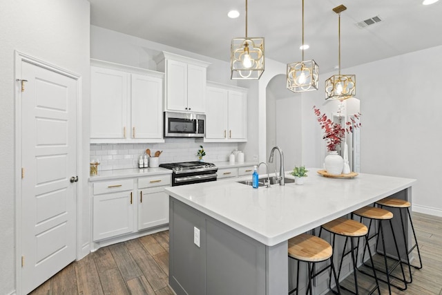 217 Magdalene Way, Liberty Hill, TX 78642 - kitchen featuring wood finished floors, stainless steel appliances, backsplash, a kitchen island with sink, and a kitchen bar