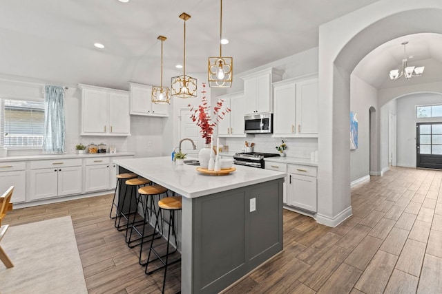 217 Magdalene Way, Liberty Hill, TX 78642 - kitchen with arched walkways, a chandelier, tasteful backsplash, a kitchen breakfast bar, and stainless steel appliances