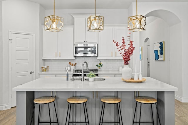 217 Magdalene Way, Liberty Hill, TX 78642 - kitchen featuring a chandelier, arched walkways, tasteful backsplash, a breakfast bar area, and white cabinets