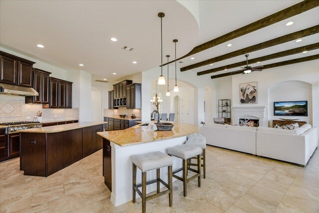 598 Naples Ln, Austin, TX 78737 - kitchen with under cabinet range hood, arched walkways, tasteful backsplash, a breakfast bar, and a center island