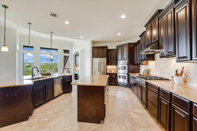 598 Naples Ln, Austin, TX 78737 - kitchen with an island with sink, appliances with stainless steel finishes, a sink, a chandelier, and arched walkways
