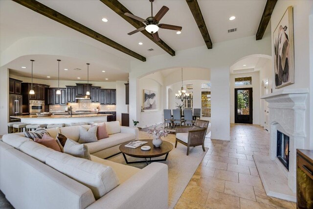 598 Naples Ln, Austin, TX 78737 - living room with arched walkways, recessed lighting, stone tile floors, beam ceiling, and a chandelier