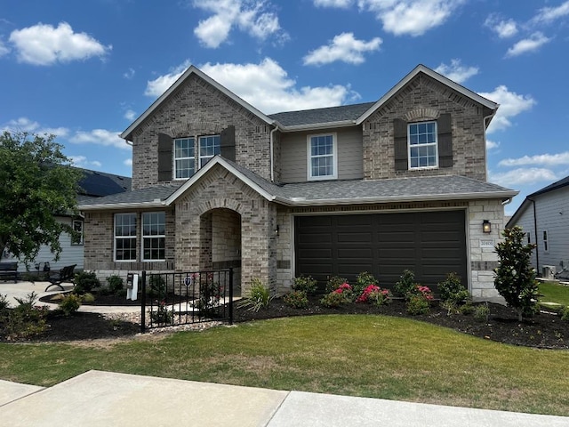 20406 Stelfox St, Manor, TX 78653 - traditional home featuring a garage, a front lawn, roof with shingles, and stone siding