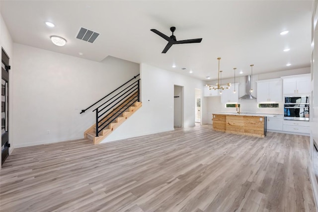 121 Mokolii Ct, Bastrop, TX 78602 - unfurnished living room with ceiling fan, light wood-type flooring, stairway, recessed lighting, and a chandelier