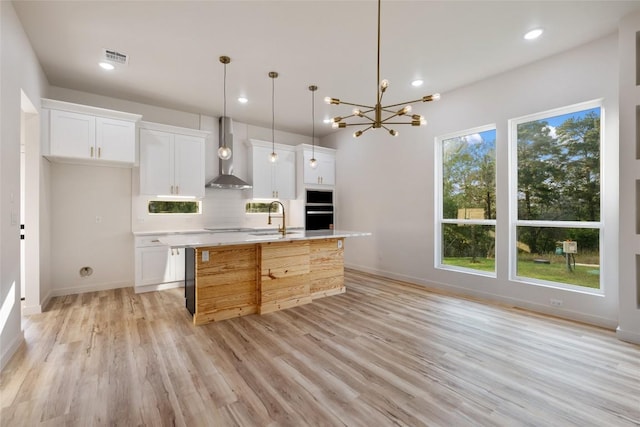 121 Mokolii Ct, Bastrop, TX 78602 - kitchen featuring wall chimney range hood, a sink, backsplash, white cabinetry, and light wood-style floors