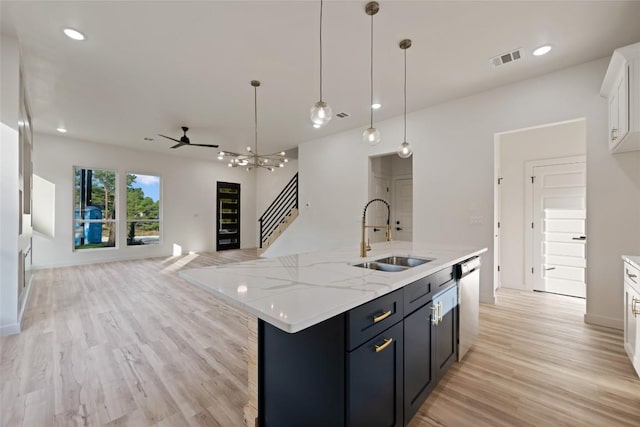 121 Mokolii Ct, Bastrop, TX 78602 - kitchen with a sink, open floor plan, dishwasher, light wood finished floors, and white cabinetry