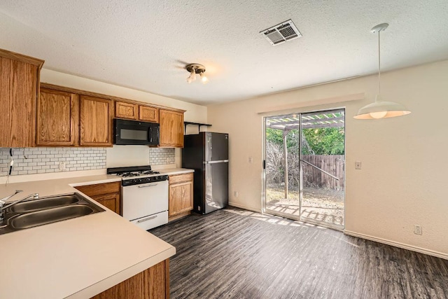 16321 Hamilton Point Cir, Manor, TX 78653 - kitchen featuring black microwave, white gas stove, freestanding refrigerator, a sink, and dark wood finished floors