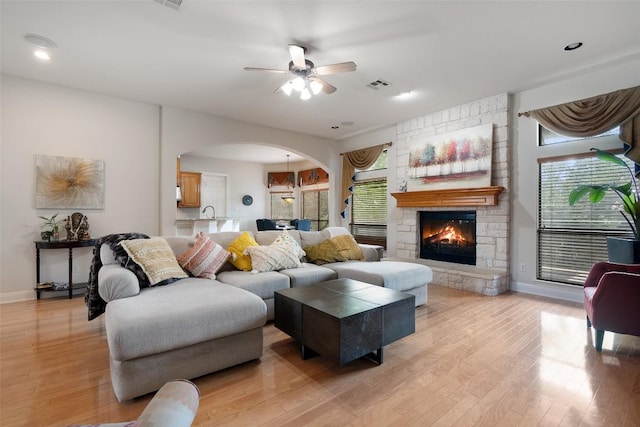9904 Chester Cv, Austin, TX 78750 - living area featuring arched walkways, a ceiling fan, a stone fireplace, light wood-type flooring, and recessed lighting