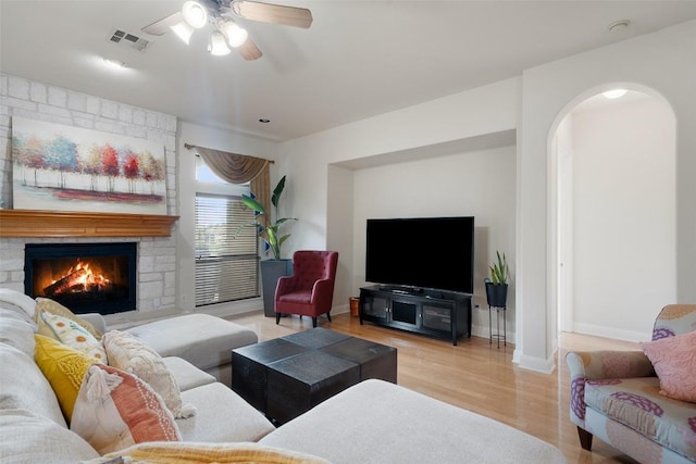 9904 Chester Cv, Austin, TX 78750 - living room with wood finished floors, arched walkways, ceiling fan, and a stone fireplace