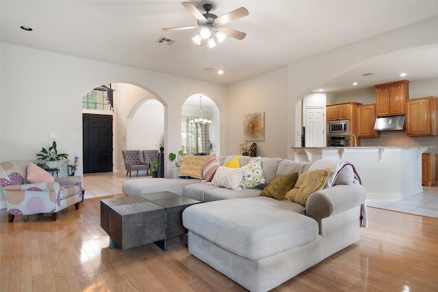 9904 Chester Cv, Austin, TX 78750 - living room with arched walkways, light wood finished floors, ceiling fan, a chandelier, and recessed lighting
