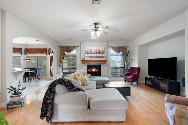 9904 Chester Cv, Austin, TX 78750 - living area with arched walkways, ceiling fan, light wood-style flooring, and a fireplace