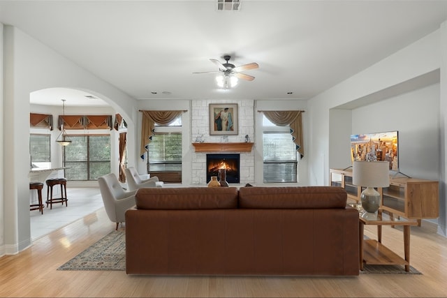 9904 Chester Cv, Austin, TX 78750 - living room with a ceiling fan, a stone fireplace, light wood-style floors, and arched walkways