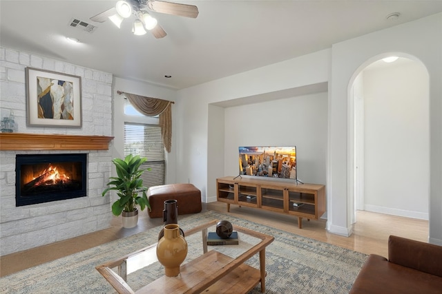 9904 Chester Cv, Austin, TX 78750 - living area featuring arched walkways, a stone fireplace, ceiling fan, and wood finished floors