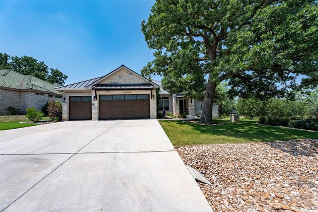 503 Fire Dance, Horseshoe Bay, TX 78657 - view of front facade featuring a garage, concrete driveway, a front lawn, a standing seam roof, and a metal roof