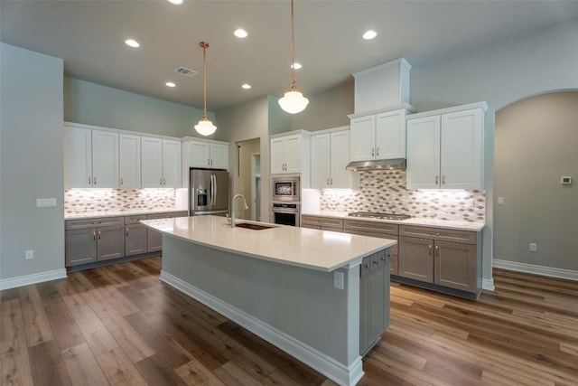 503 Fire Dance, Horseshoe Bay, TX 78657 - kitchen featuring a sink, appliances with stainless steel finishes, under cabinet range hood, a center island with sink, and tasteful backsplash
