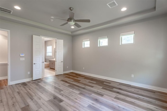 503 Fire Dance, Horseshoe Bay, TX 78657 - unfurnished bedroom featuring a tray ceiling, wood finished floors, a spacious closet, recessed lighting, and connected bathroom
