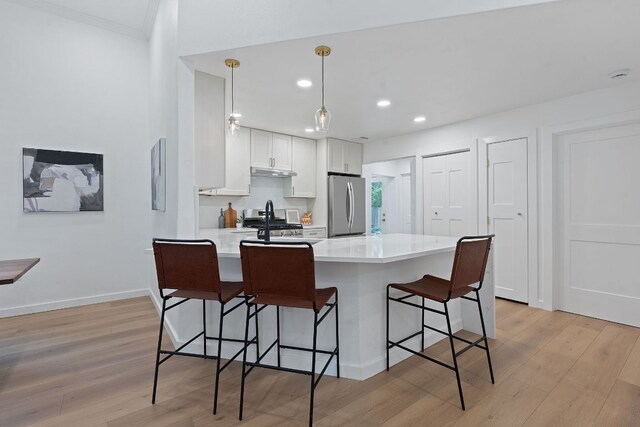 1607 Forest St, Georgetown, TX 78626 - kitchen featuring freestanding refrigerator, a breakfast bar, light wood finished floors, under cabinet range hood, and recessed lighting