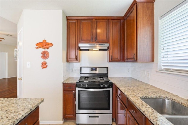 3005 Sugar Berry Cv, Round Rock, TX 78664 - kitchen with stainless steel gas range oven, under cabinet range hood, decorative backsplash, and light stone counters