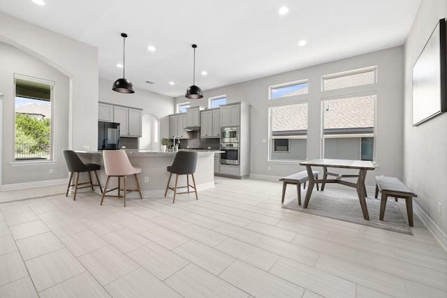 108 Panzano Dr, Georgetown, TX 78628 - kitchen with appliances with stainless steel finishes, gray cabinetry, a kitchen breakfast bar, healthy amount of natural light, and recessed lighting