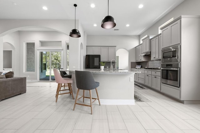 108 Panzano Dr, Georgetown, TX 78628 - kitchen with stainless steel appliances, gray cabinets, tasteful backsplash, arched walkways, and recessed lighting