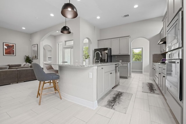 108 Panzano Dr, Georgetown, TX 78628 - kitchen featuring stainless steel oven, gray cabinets, arched walkways, tasteful backsplash, and recessed lighting