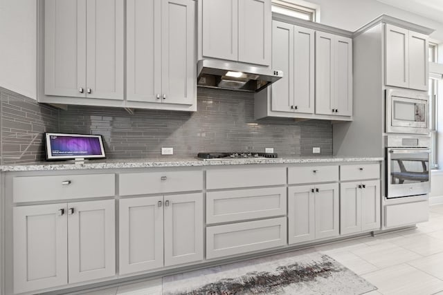 108 Panzano Dr, Georgetown, TX 78628 - kitchen with stainless steel appliances, exhaust hood, tasteful backsplash, and light stone countertops