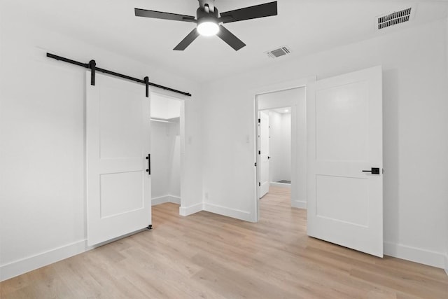 813 Cardiff Dr, Austin, TX 78745 - unfurnished bedroom with a barn door, baseboards, and light wood-type flooring