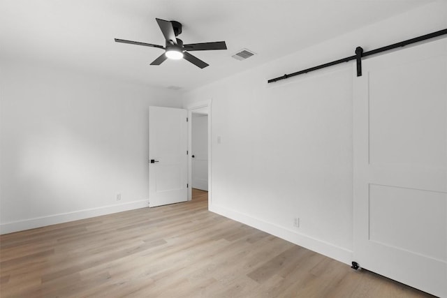 813 Cardiff Dr, Austin, TX 78745 - unfurnished bedroom featuring a barn door, light wood-type flooring, baseboards, and a ceiling fan