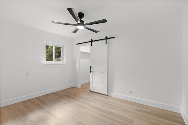 813 Cardiff Dr, Austin, TX 78745 - unfurnished room with a barn door, ceiling fan, light wood-style floors, and baseboards