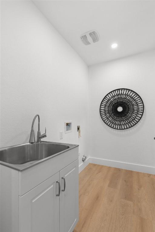 813 Cardiff Dr, Austin, TX 78745 - washroom featuring hookup for a washing machine, hookup for an electric dryer, baseboards, light wood-style flooring, and cabinet space