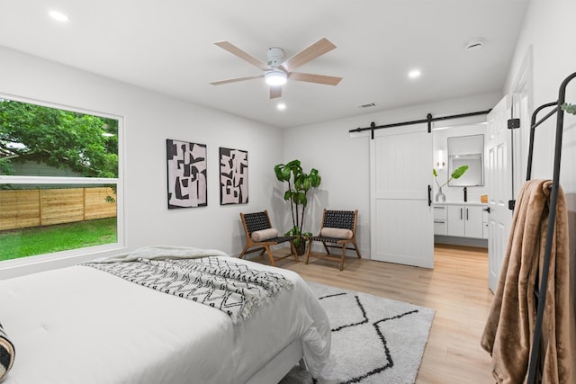 903 Cardiff Dr, Austin, TX 78745 - bedroom featuring a barn door, light wood finished floors, recessed lighting, a ceiling fan, and connected bathroom
