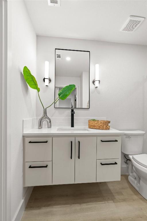 903 Cardiff Dr, Austin, TX 78745 - bathroom with vanity, wood finished floors, toilet, and baseboards