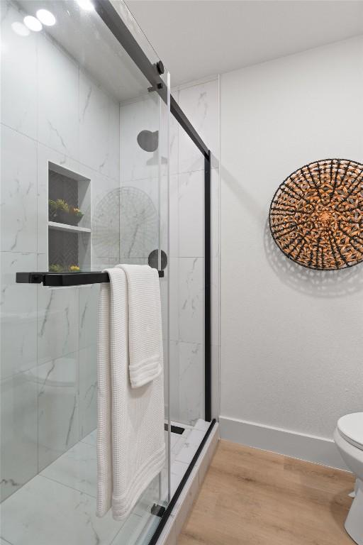 903 Cardiff Dr, Austin, TX 78745 - full bath featuring a marble finish shower, toilet, wood finished floors, and baseboards