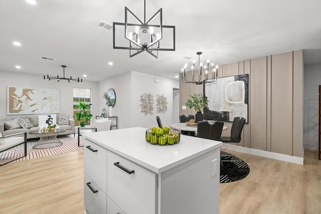 903 Cardiff Dr, Austin, TX 78745 - kitchen with a chandelier, light wood finished floors, a kitchen island, light countertops, and recessed lighting