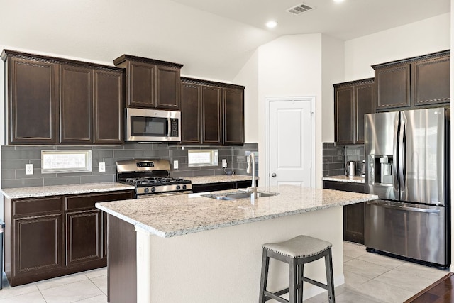 5012 Yucca Bloom Dr, Georgetown, TX 78626 - kitchen with stainless steel appliances, a sink, vaulted ceiling, dark brown cabinets, and backsplash