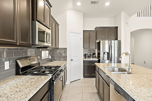 5012 Yucca Bloom Dr, Georgetown, TX 78626 - kitchen featuring appliances with stainless steel finishes, a sink, arched walkways, dark brown cabinets, and recessed lighting