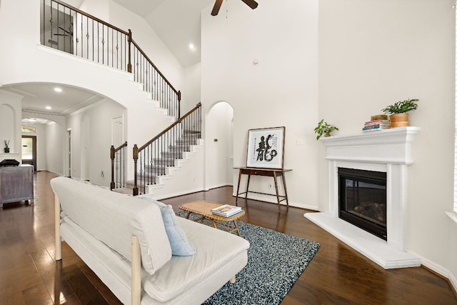 5012 Yucca Bloom Dr, Georgetown, TX 78626 - living room with arched walkways, a glass covered fireplace, ceiling fan, a high ceiling, and wood finished floors