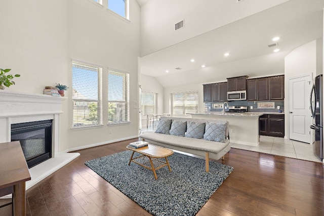 5012 Yucca Bloom Dr, Georgetown, TX 78626 - living area featuring a towering ceiling, plenty of natural light, light wood-style flooring, a glass covered fireplace, and recessed lighting